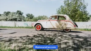 Cream vintage car driving down a sunny road